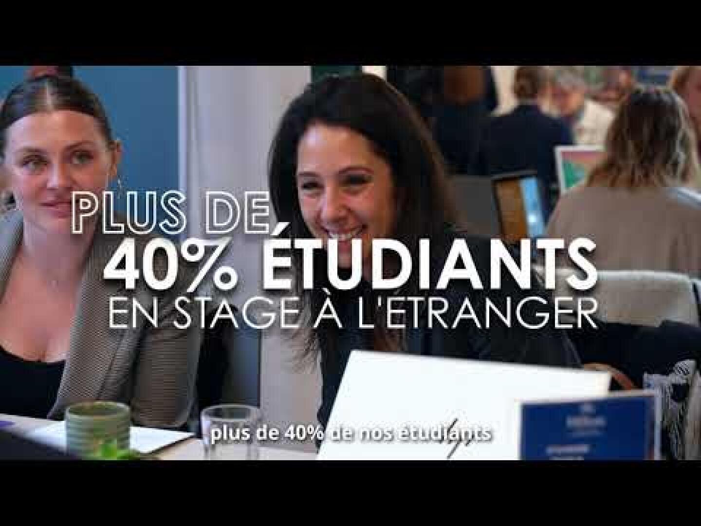 Deux femmes assises à une table, souriantes, avec une inscription en français en surimpression indiquant « Plus de 40 % des étudiants effectuent un stage à l'étranger ».