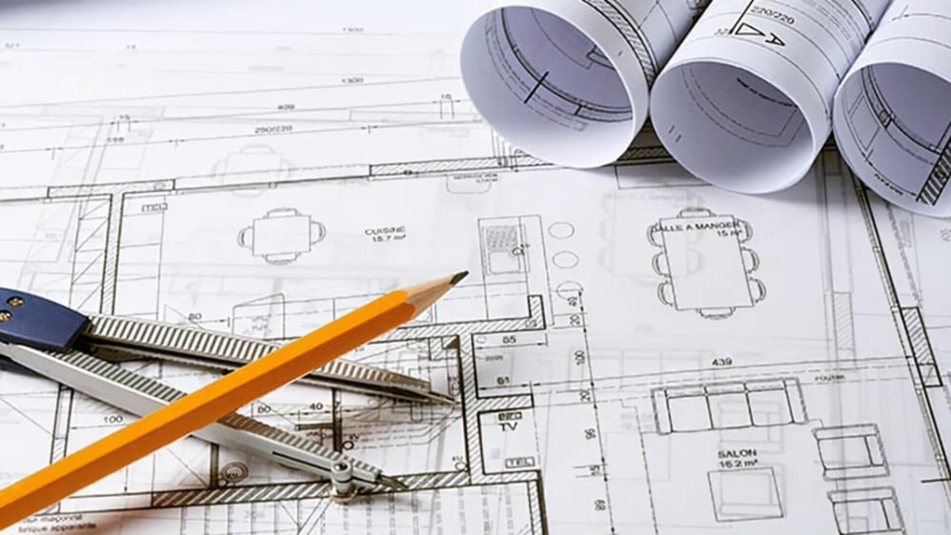 Gros plan sur des plans d'architecture avec un crayon jaune, un compas métallique et trois plans enroulés posés sur les dessins.