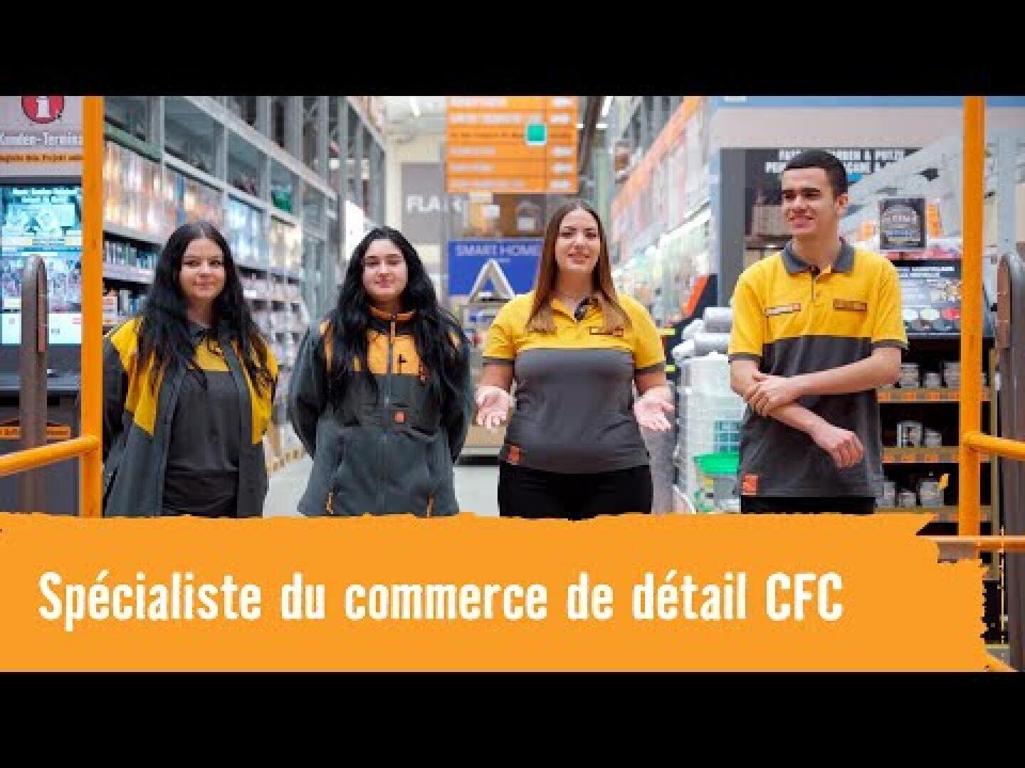 Quatre employés en uniforme sourient à l'intérieur d'un rayon de quincaillerie. Une banderole orange en bas de l'allée indique : "Spécialiste du commerce de détail CFC" : Spécialiste du commerce de détail CFC. Des étagères contenant des produits se trouvent à l'arrière-plan.