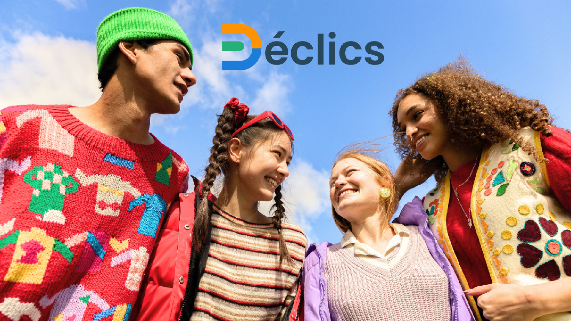 Quatre jeunes gens souriants, vêtus de pulls et de vestes colorés, se tiennent ensemble en plein air sous un ciel bleu. Le mot Déclics avec un logo multicolore est affiché au-dessus d'eux.