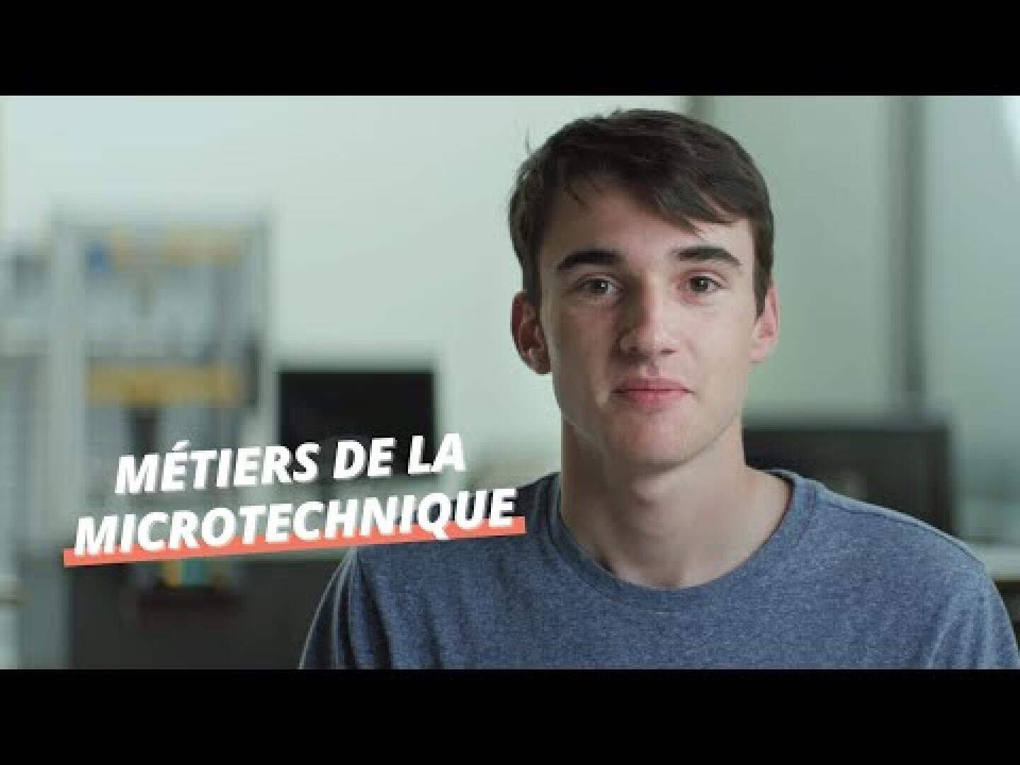 Un jeune homme aux cheveux bruns courts et à la chemise bleue regarde la caméra. Sur l'image, on peut lire en blanc « Métiers de la microtechnique ». L'arrière-plan est un décor intérieur flou.
